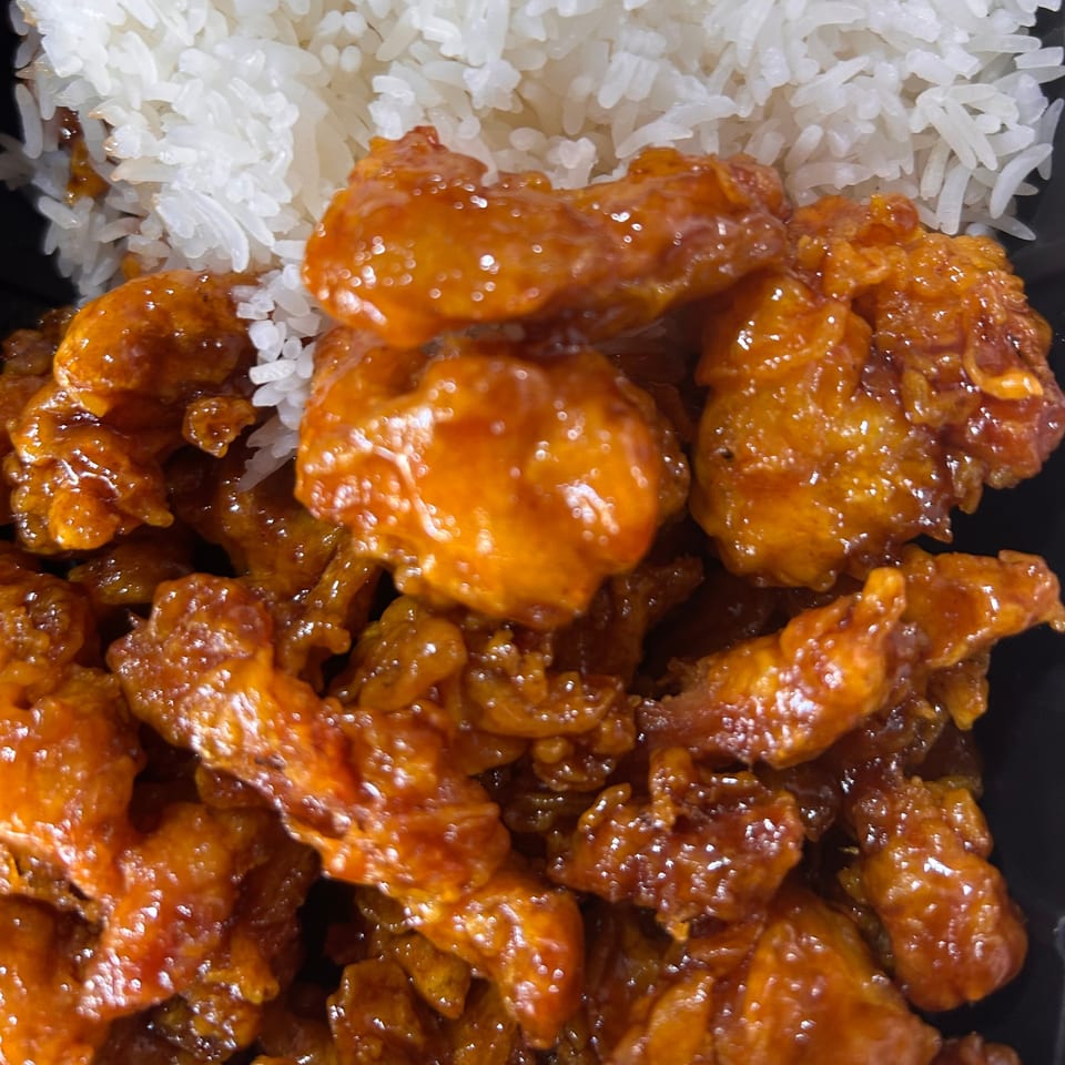 Tuk Tuk Express's orange chicken, glistening with sauce, served alongside fluffy white rice.
