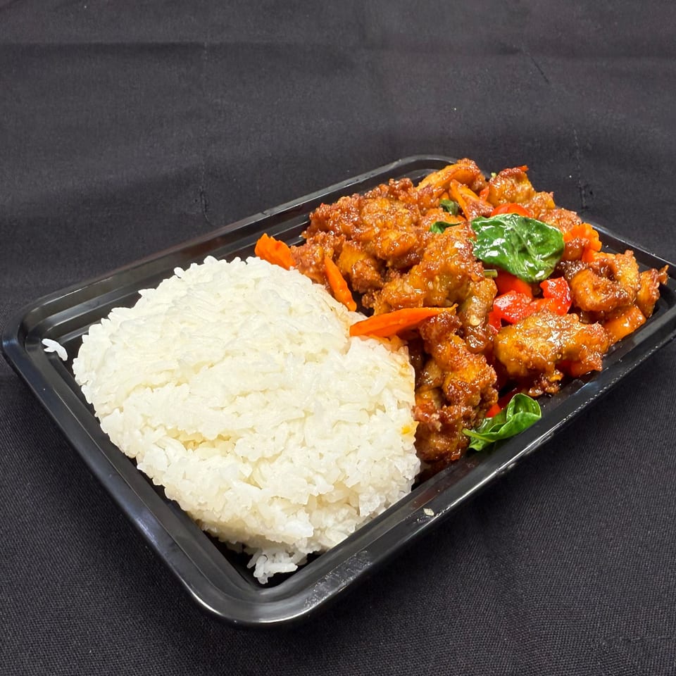 Tuk Tuk Express's Thai basil chicken with white rice, red bell peppers, and basil leaves in a black container.