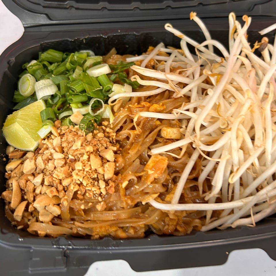 Tuk Tuk Express Pad Thai with noodles, bean sprouts, peanuts, green onions, and a lime wedge.